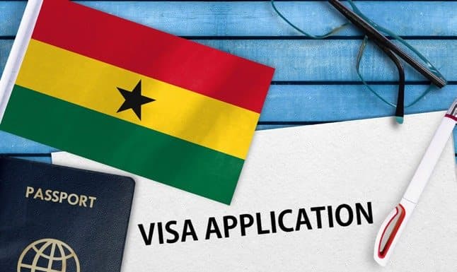 A Ghanaian flag, a passport and a visa application form on a desk