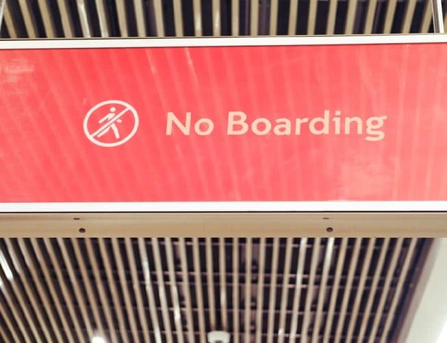 A red 'No Boarding' sign hanging in an airport terminal
